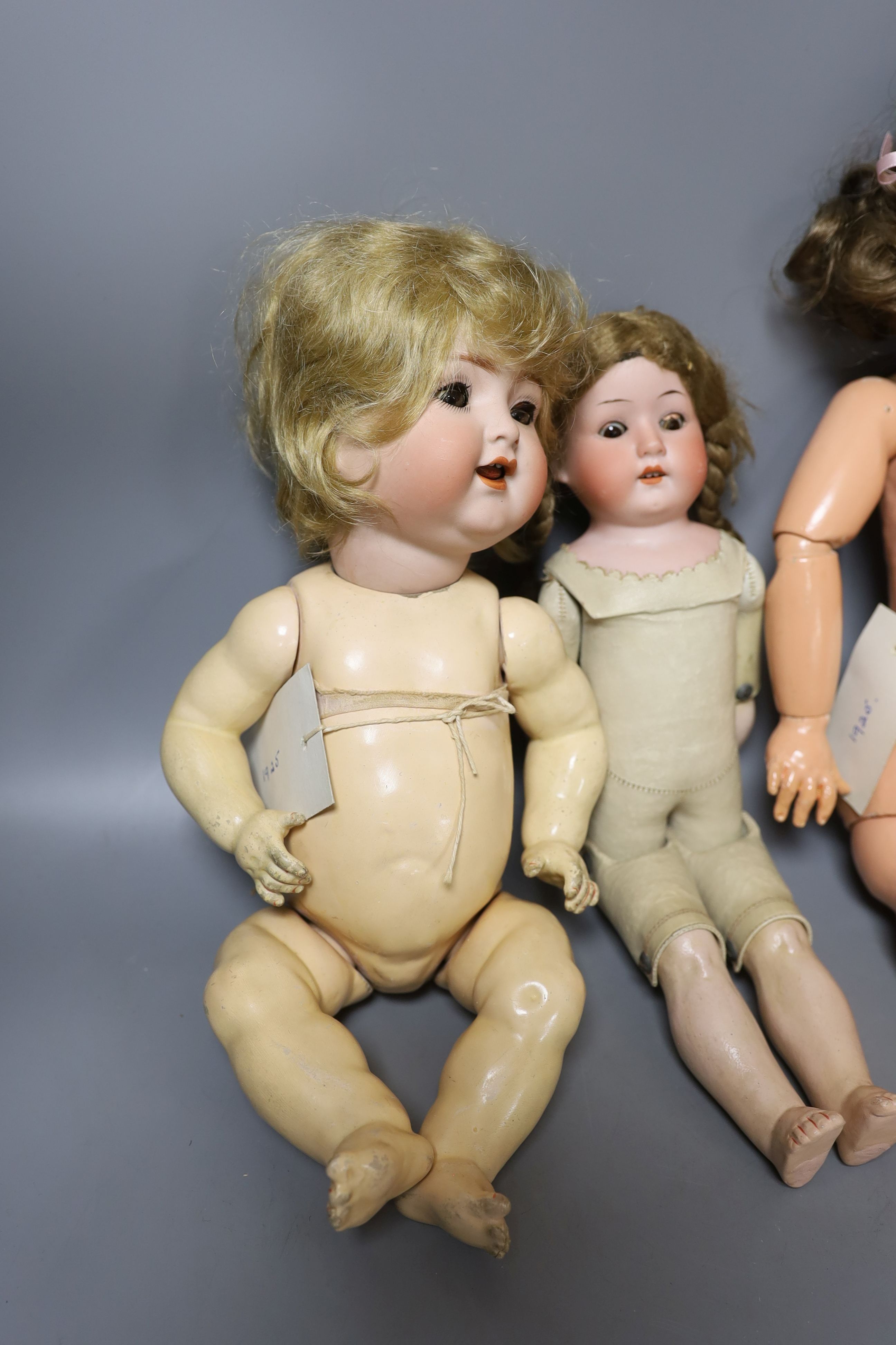 A kid leather bodied jointed limb open mouth Heubach bisque headed doll together with two other bisque headed dolls and a boy doll (damaged)